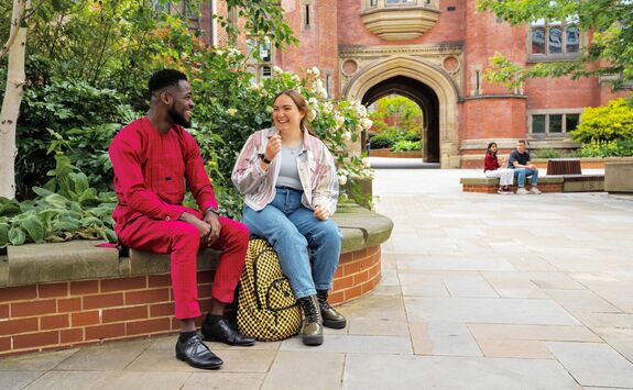 Two students sat outside on campus, laughing together